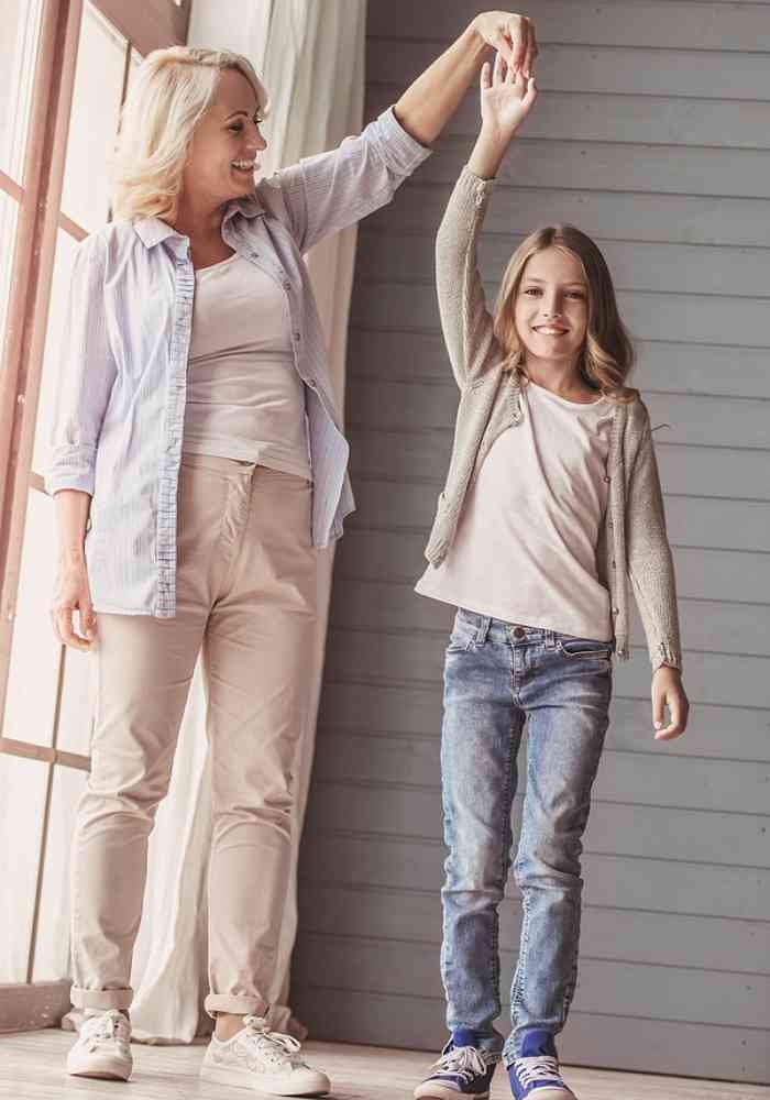 Photograph of a grandma and a granddaughter. The granddaughter is age 10-11 and has her right arm up in the air and the grandma is holding her hand, like she is going to twirl her around. They are both in casual clothes, standing on a porch. Used to illustrate prayers for my granddaughter.