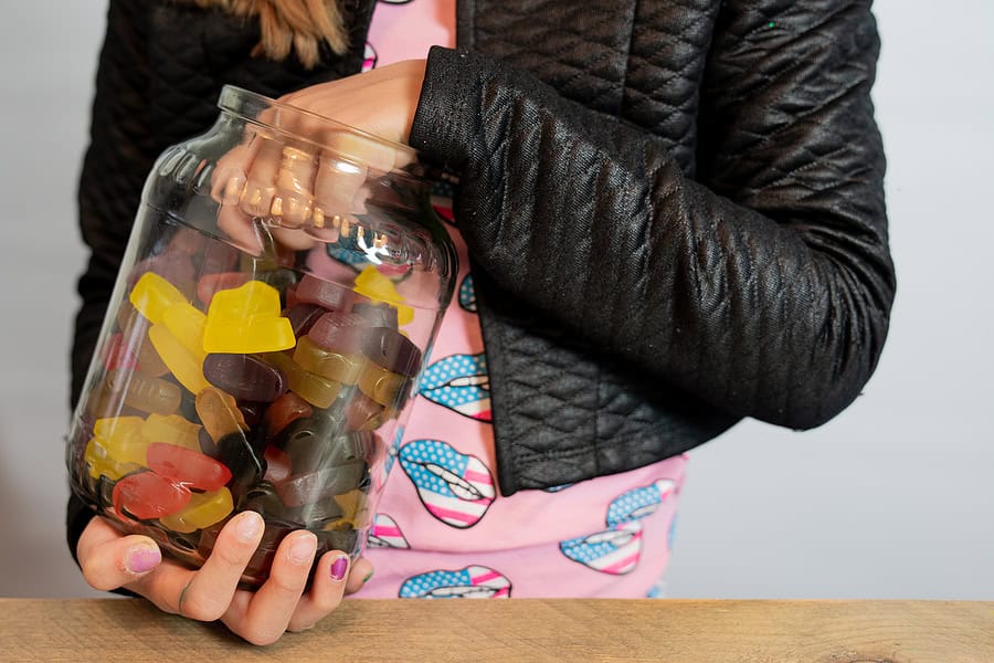 A photograph of a girl of about 12-13 years old with her hand in a candy jar. The photo does not show her face She is in a pink tshirt with a black jacket. This is used to illustrate temptation in the post prayers for my granddaughter.