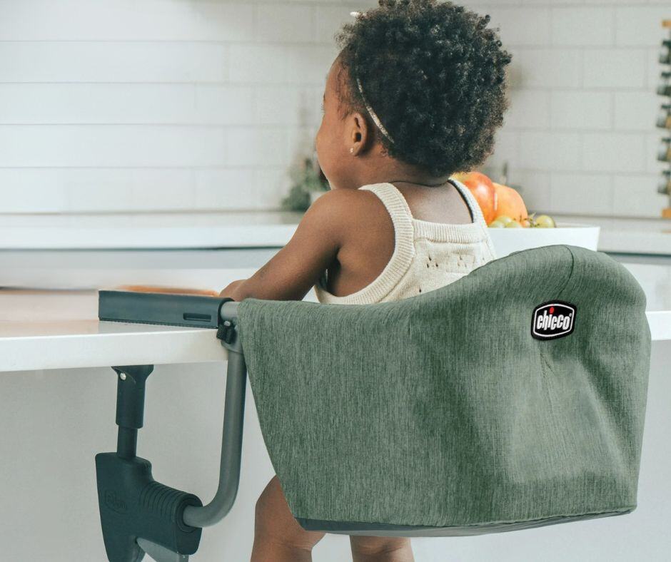 Picture of a little girl sitting in a clip on baby seat. The girl has her back to the camera and looks like she is waiting for a meal. Used to illustrate the blog post What does a first-time grandma need?