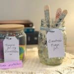 Photo of 2 prayer jars. They are sitting side by side on a doily with 3 books stacked behind them. The jar on the right has a tag that says Grandma's Prayer Jar. The prayer jar on the left has a tag that says Prayers for my Grandchildren.