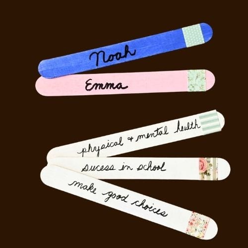 Photo of 5 popsicle sticks that can be used in a prayer jar. The first stick is blue and has the name Noah written on it. The second stick is pink and has the name Emma written on it. The next 3 sticks are white and have prayer requests written on them.