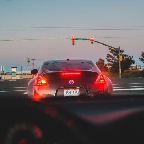 Photo from the inside of a car from the driver's perspective. They are sitting at a stop light. There is one car in front of them, with their brake lights on. Used to illustrate the post Remember to Pray - the section about praying while you wait for something.